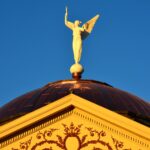Winged Victory statue on the copper dome of the Arizona Capitol Museum against a blue sky