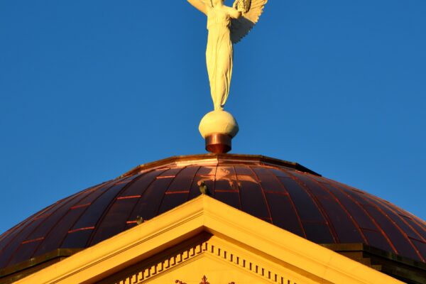 Winged Victory statue on the copper dome of the Arizona Capitol Museum against a blue sky