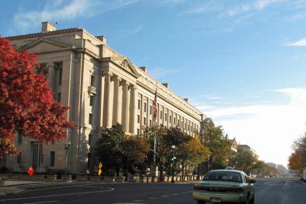 Exterior of the U.S. Department of Justice building along a tree-lined street