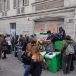 Teenage students gathered on a Paris sidewalk outside a blockaded high school entrance