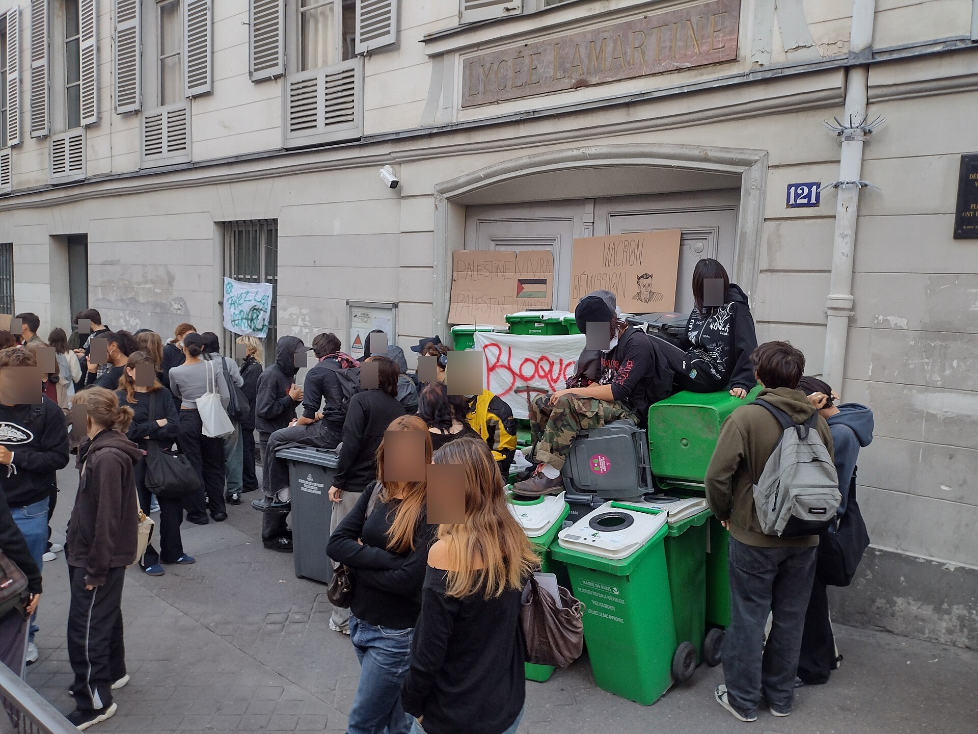 Teenage students gathered on a Paris sidewalk outside a blockaded high school entrance