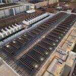 Aerial view of a large data center roof lined with cooling units and generators