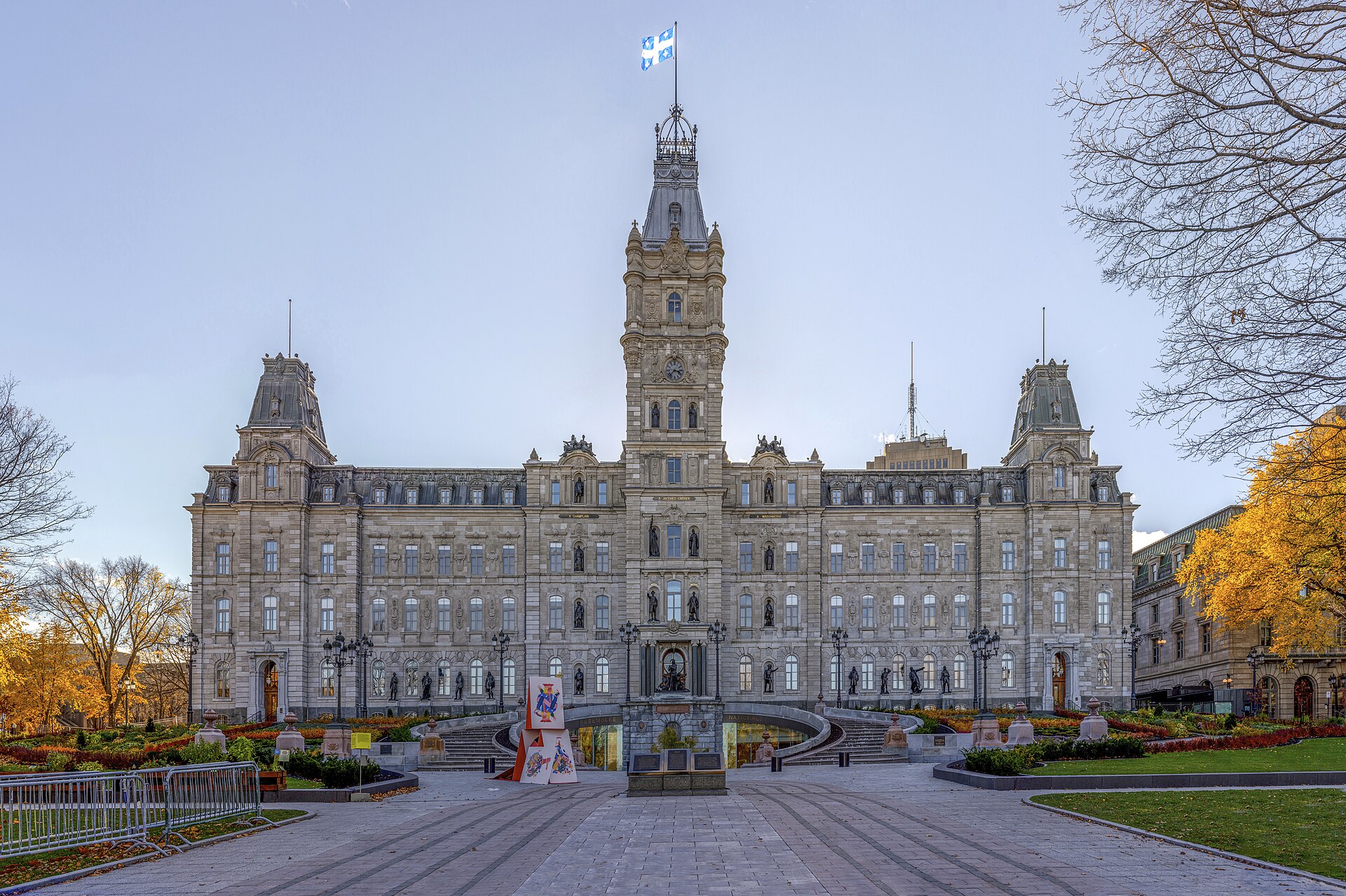 The ornate stone Parliament Building of Quebec with a central clock tower and autumn trees