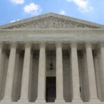 White marble columns and facade of the U.S. Supreme Court building under a blue sky