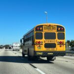 Rear view of a yellow school bus driving on a Florida highway