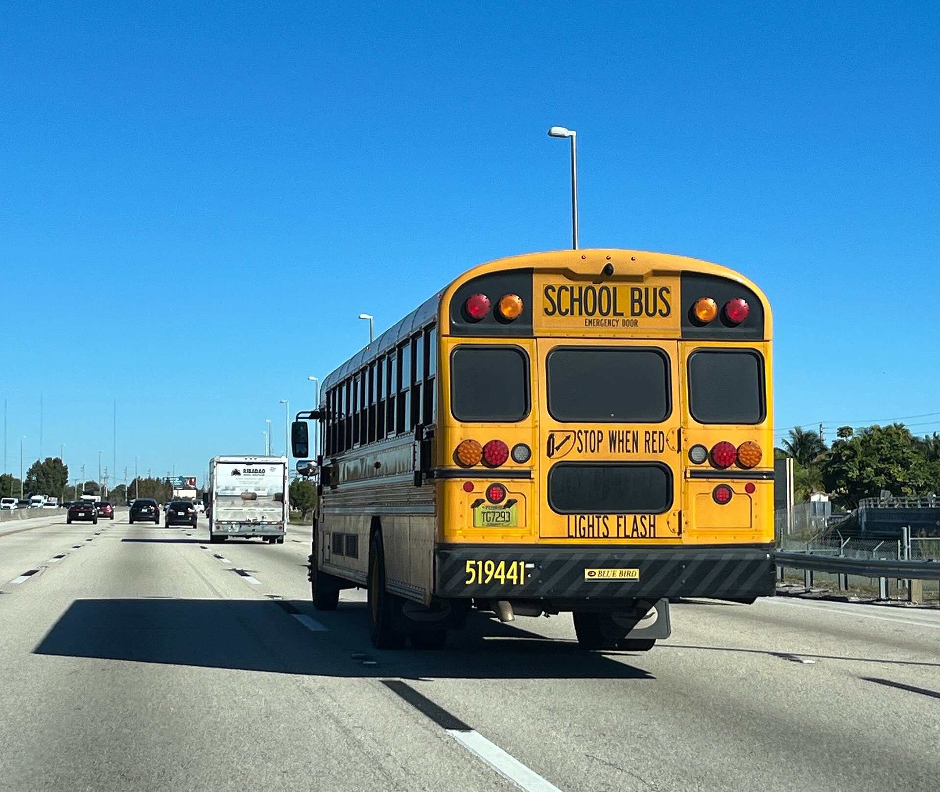 Rear view of a yellow school bus driving on a Florida highway